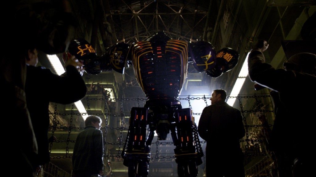 Down-on-his-luck fight promoter Charlie Kenton (Hugh Jackman, right) and his son, Max (Dakota Goyo, left) introduce their star robot boxer Noisy Boy to the cheering crowd at the Crash Palace in DreamWorks Pictures' action drama "Real Steel"  ©DreamWorks II Distribution Co., LLC. ÊAll Rights Reserved.